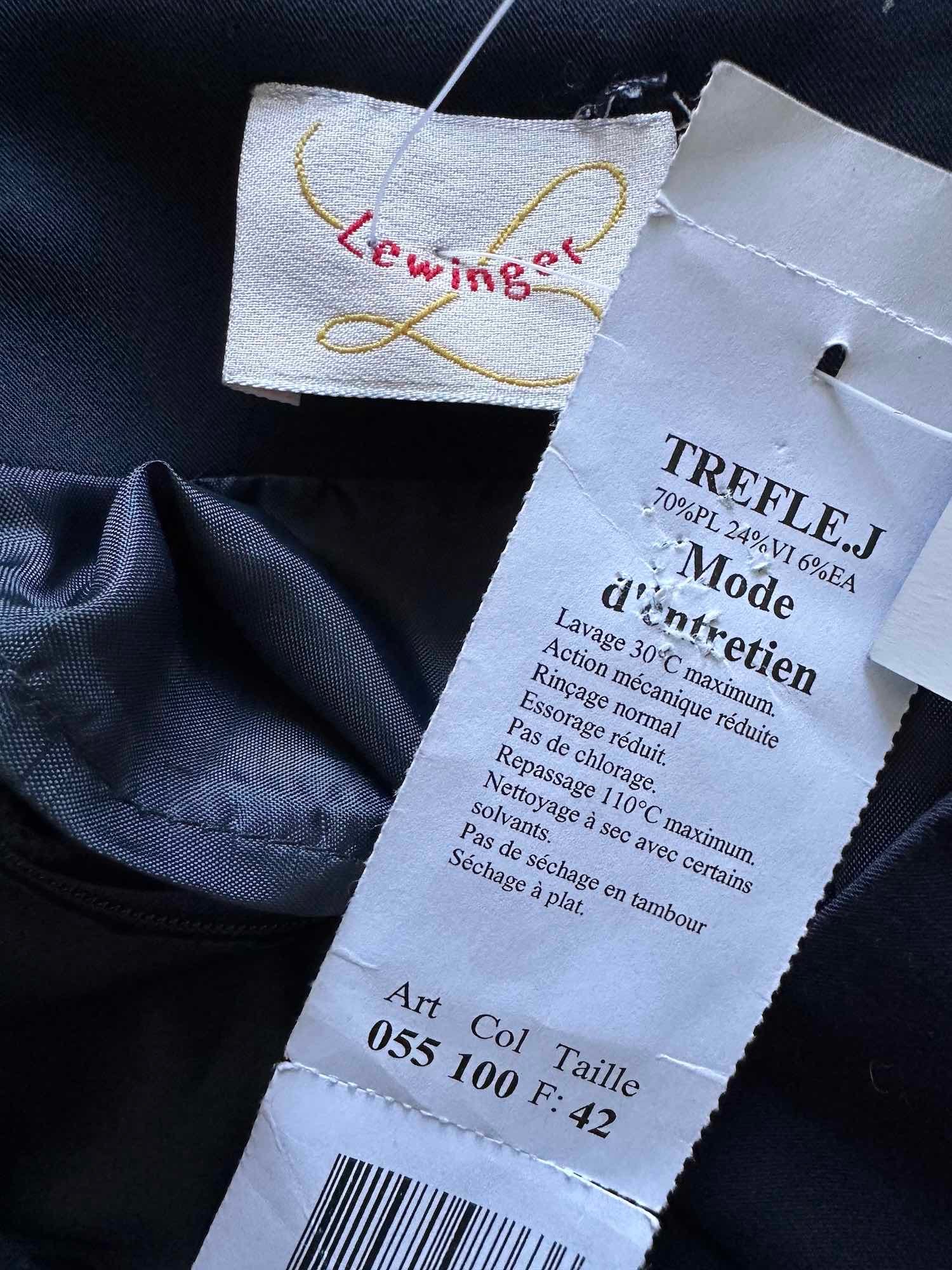 Gros plan sur l'étiquette d'une jupe neuve Lewinger taille 42 (70% polyester, 24% viscose, 6% élasthanne), l'occasion idéale à saisir sur notre friperie en ligne.