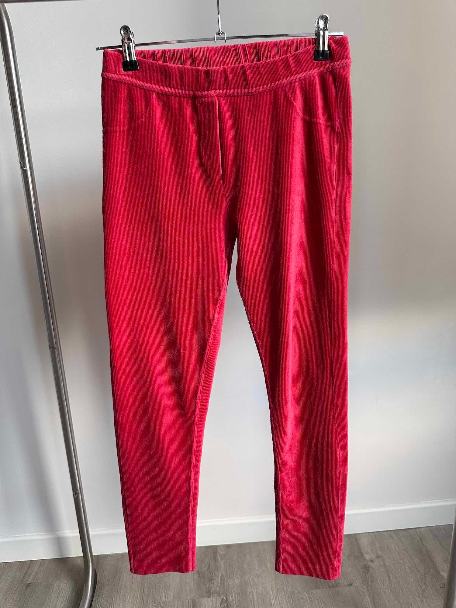 Vue de face d'un pantalon en velours côtelé rouge pour fille suspendu sur un cintre.