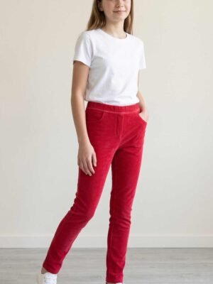 Jeune fille souriante portant un pantalon en velours rouge Orchestra avec un t-shirt blanc