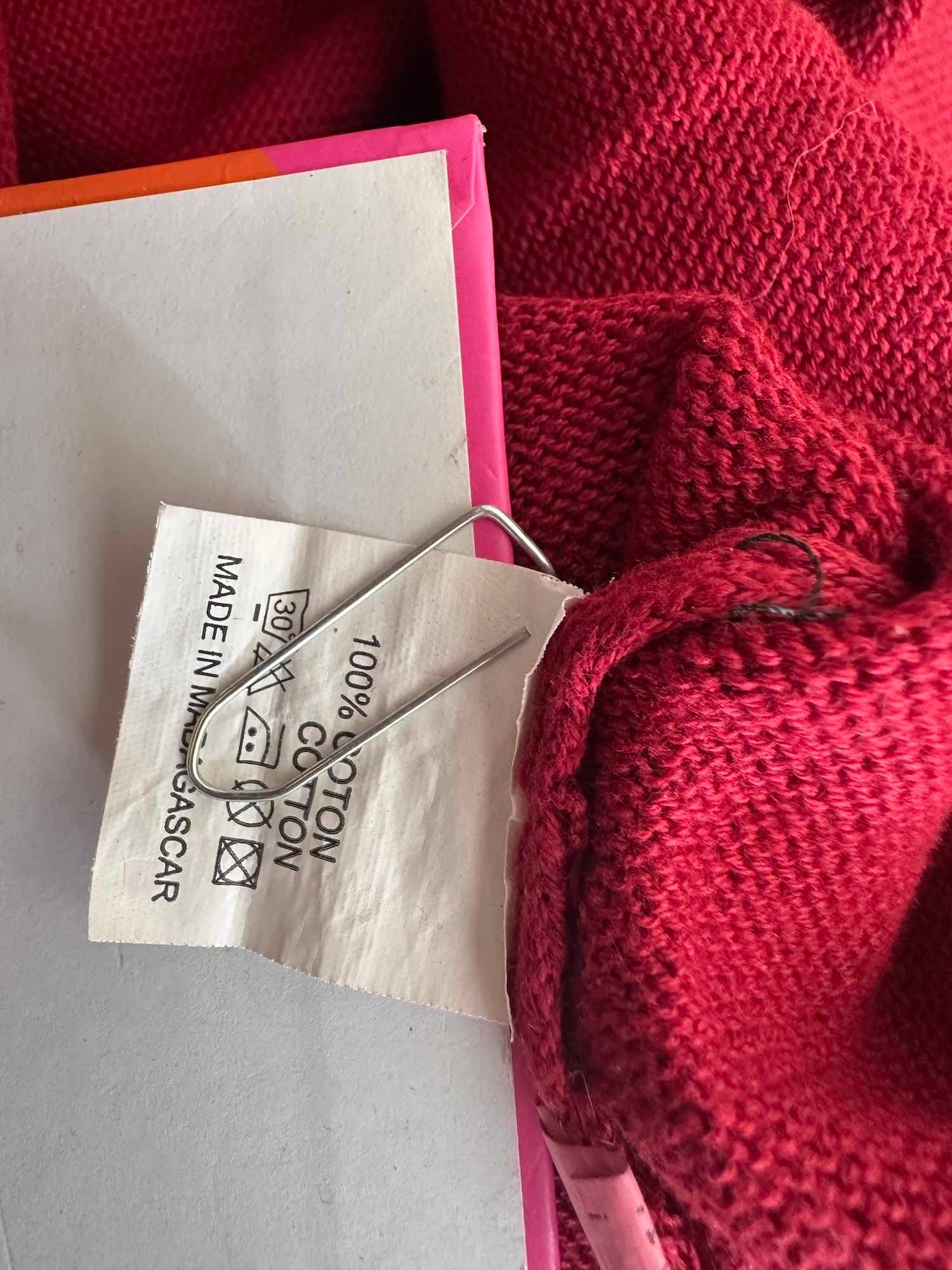 Gros plan sur l'étiquette du pull indiquant 100% coton et la fabrication à Madagascar.