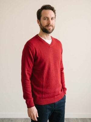 Homme portant un pull rouge à col V de la marque Saint-Pierre, vue de trois quarts face.